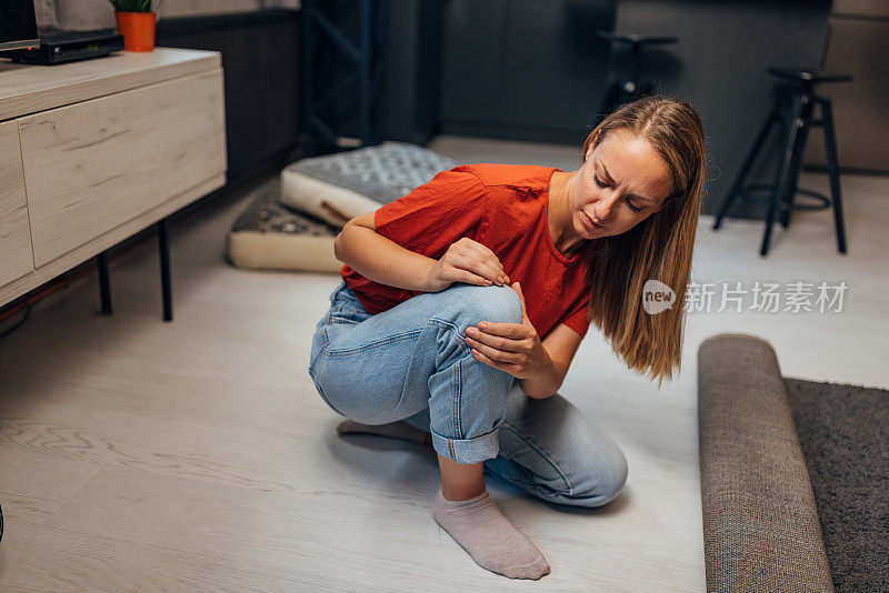 一个女人在打扫房子的时候把手放在膝盖上的一个疼痛的地方