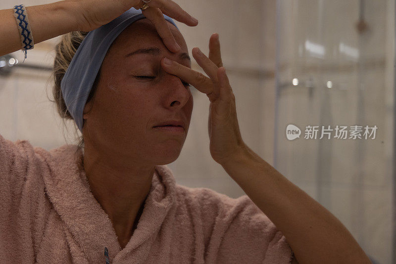 女人在浴室里往脸上涂面膜
