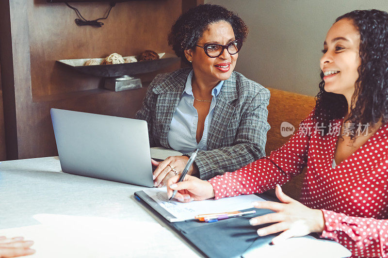 两个多种族的职业女性，同事，合作伙伴，或者客户和代理人，带着笔记本电脑