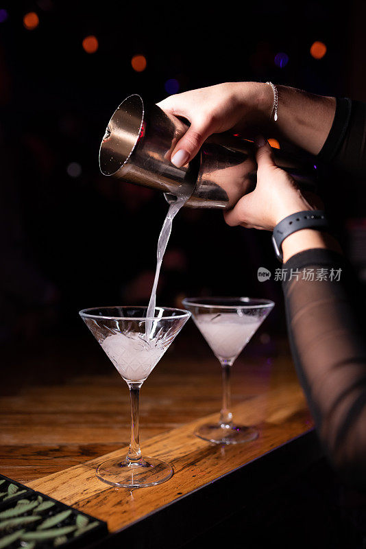 调酒师将调酒器中的酒精鸡尾酒倒入长柄玻璃杯中。在夜总会、酒吧、餐馆调制酒精鸡尾酒