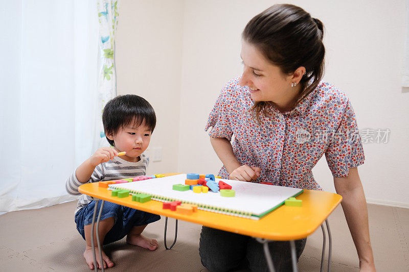 白种妇女教英文给亚洲幼童字母块