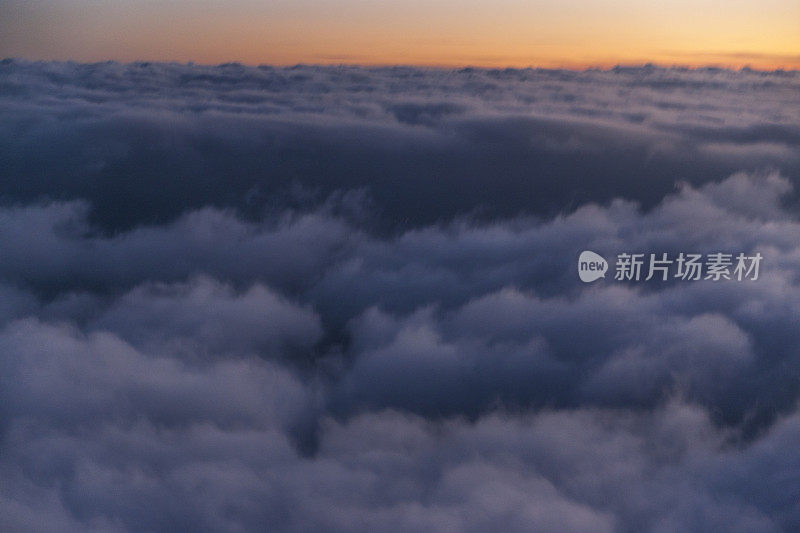 在日落时飞过云层。从飞机窗口观看