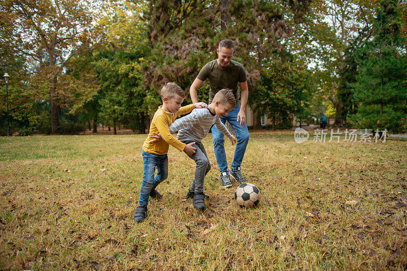 爸爸和孩子们在公园里踢足球