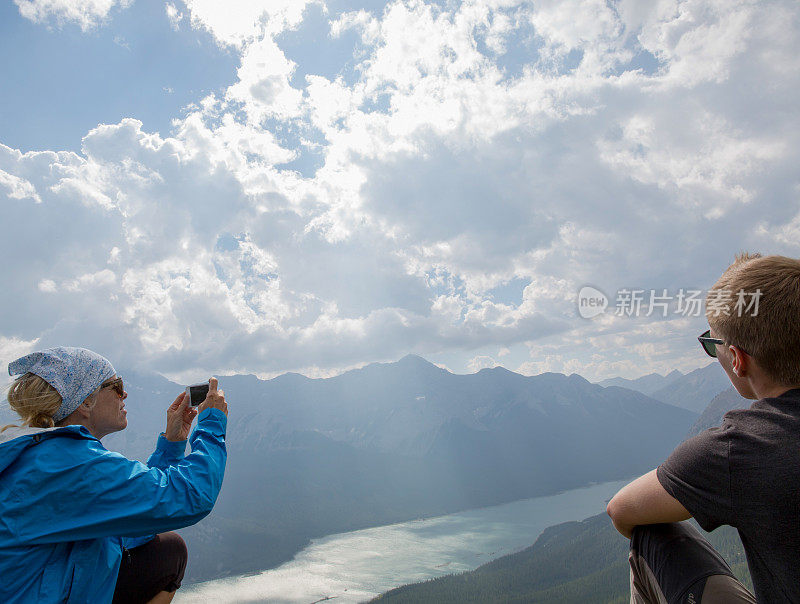 徒步旅行者拍摄阳光穿过云层和山脉中的湖泊的照片