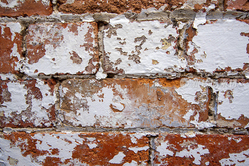 白漆剥落的旧红砖墙。