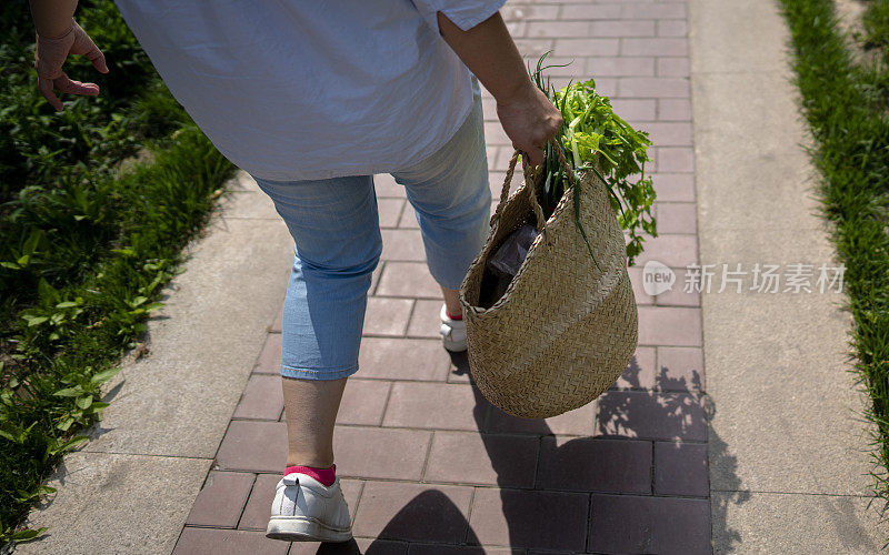 年轻女子提着菜篮子走路