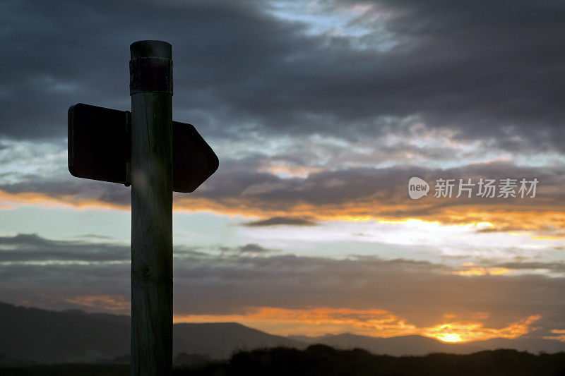 步道路标，山川云景和夕阳背景。
