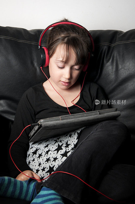 女孩用耳机在平板电脑上听音乐