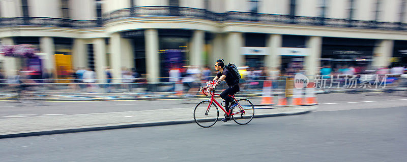 骑自行车的人骑自行车快速穿过城市。速度模糊