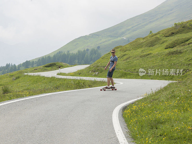 年轻人沿着山路长板而下