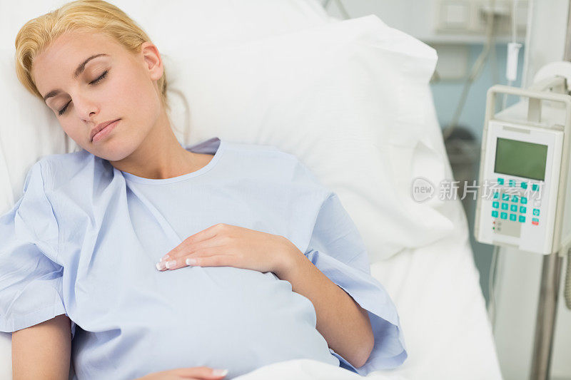 睡觉的孕妇躺在床上，同时抱着她的肚子