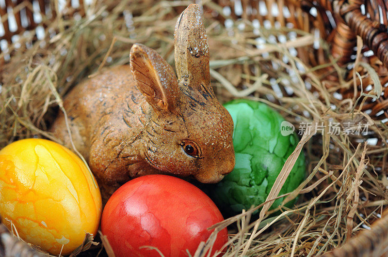 塑料复活节兔子坐在稻草窝和复活节蛋