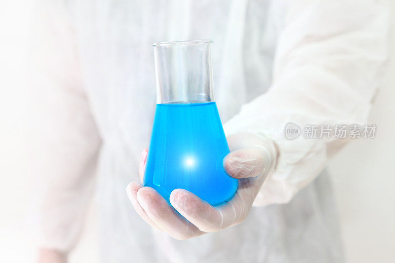 科学发现，生物学家拿着装有蓝色液体的化学玻璃烧瓶