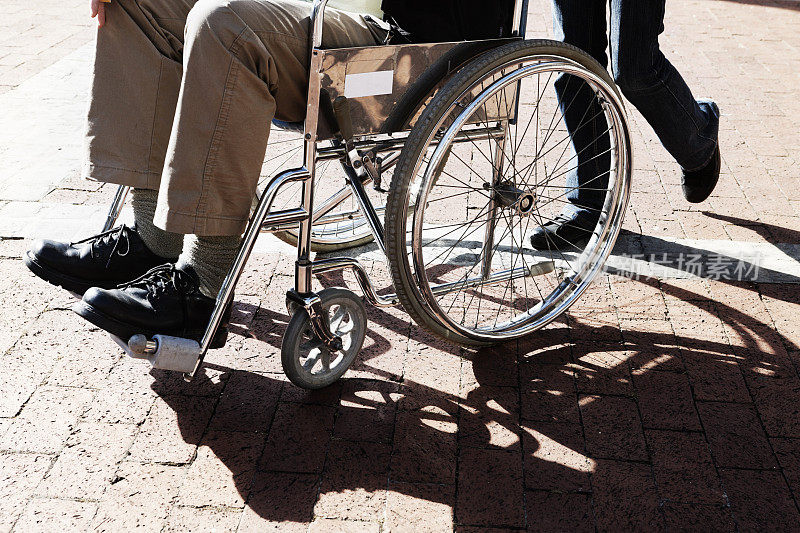 一名坐轮椅的男子被推过停车场