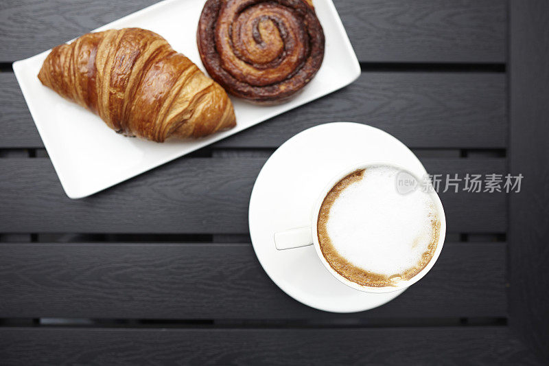 羊角面包丹麦糕点和卡布奇诺饮料在桌面上视图
