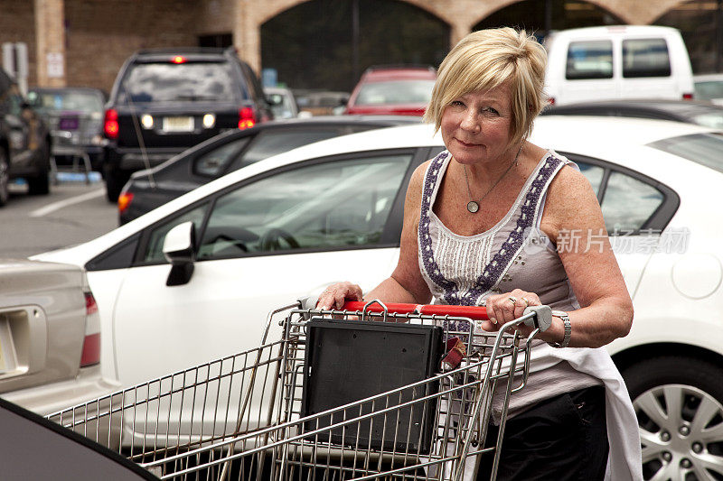 一个女人在超市停车场微笑着推着购物车
