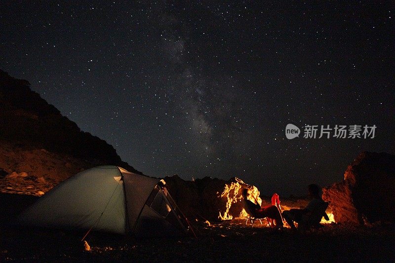 繁星点点的夜空，帐篷，篝火和草地的剪影