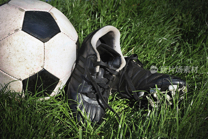 在高高的绿色草地上穿的足球和球鞋