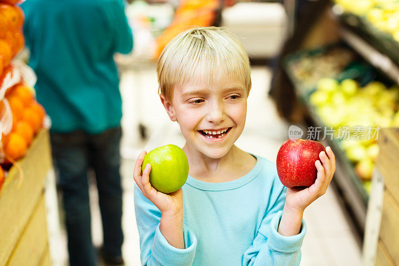 哪一个?小女孩拿着两个苹果在超市里笑
