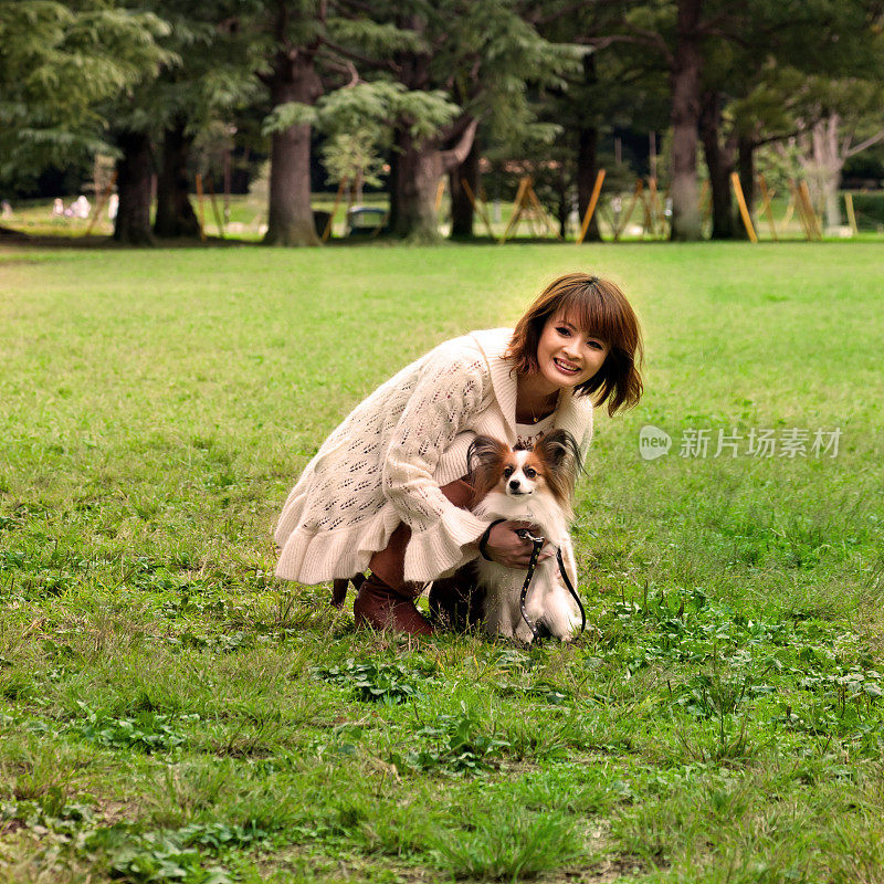 遛狗的日本妇女在公园里和宠物玩耍