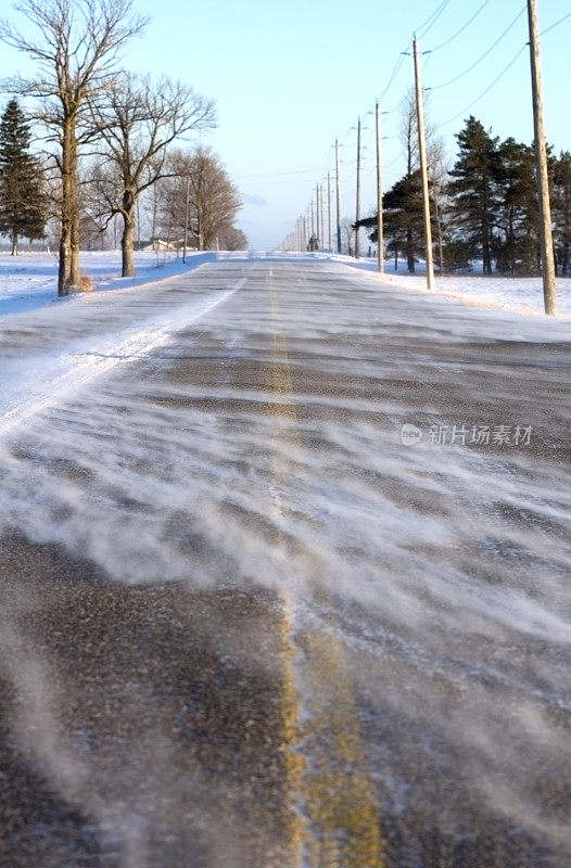 空旷的道路上覆盖着积雪，两旁是光秃秃的树木