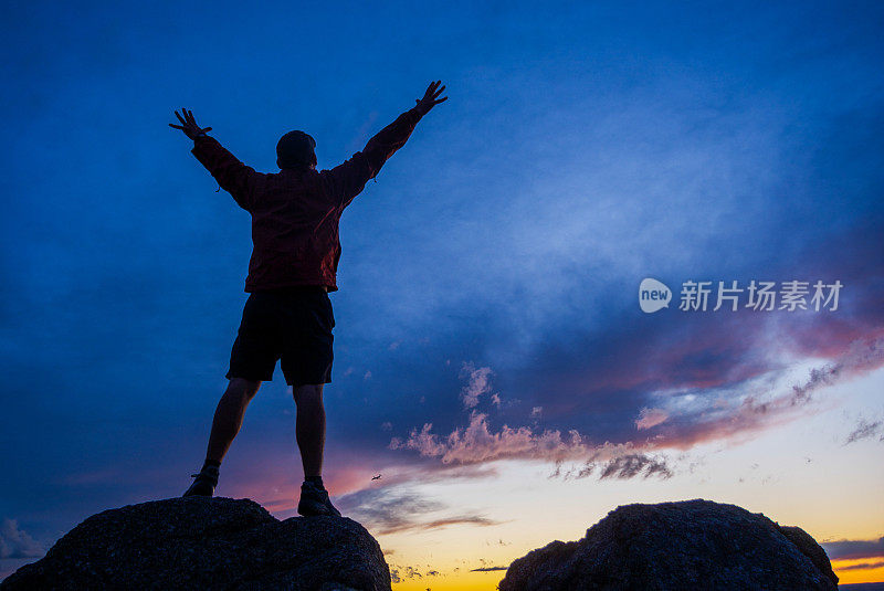 剪影的男人举起手臂进入日落的天空景观