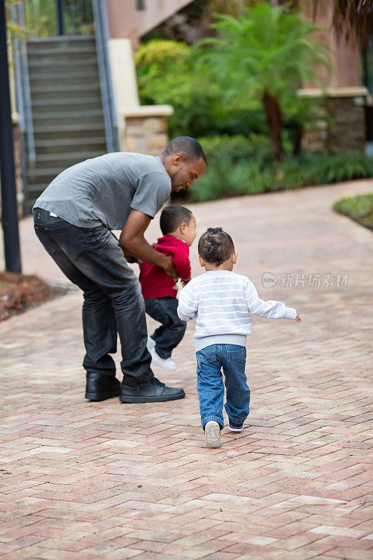 单身黑人父亲和两岁的双胞胎男孩玩耍