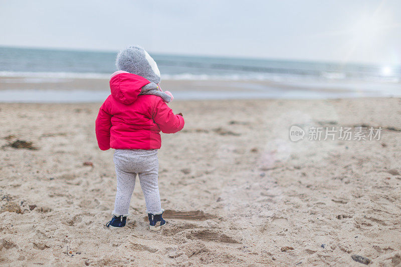 蹒跚学步的女孩独自在冬天的海滩上