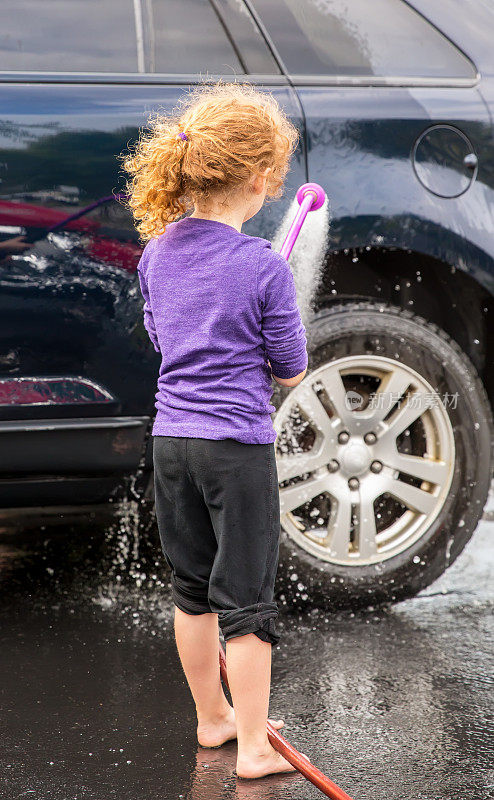 年轻女孩在车道上洗车