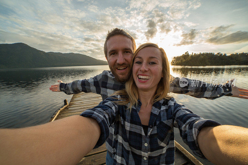一对年轻夫妇在湖边的码头上自拍