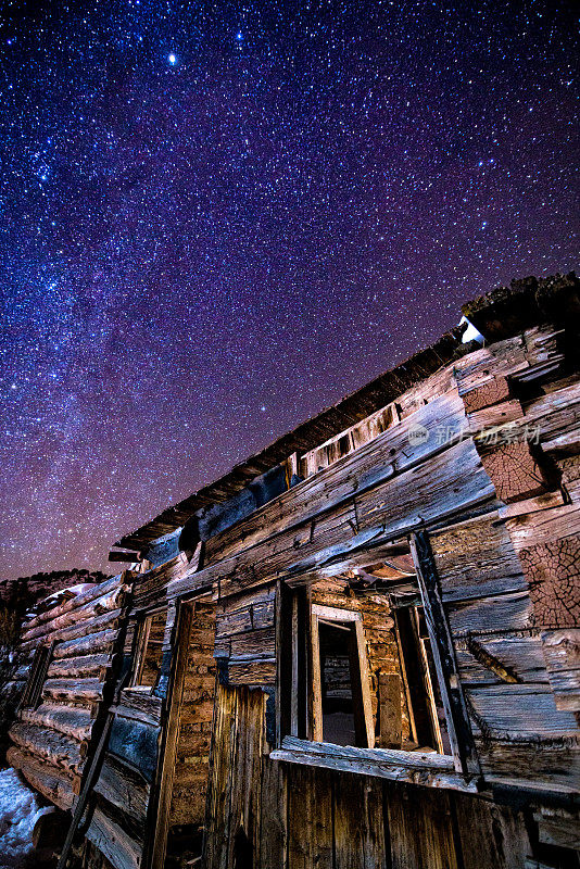 在夜晚有星星的老木屋宅地