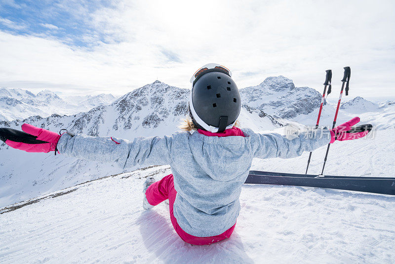 年轻女子在滑雪坡上伸开双臂