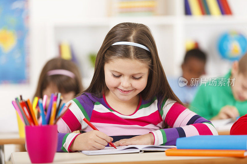 年轻女孩坐在课桌和写作考试