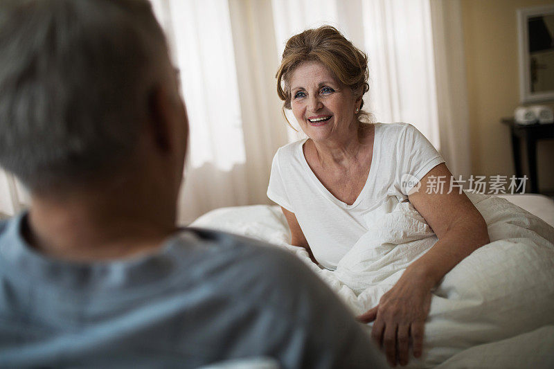 快乐的老女人在床上和丈夫说话。