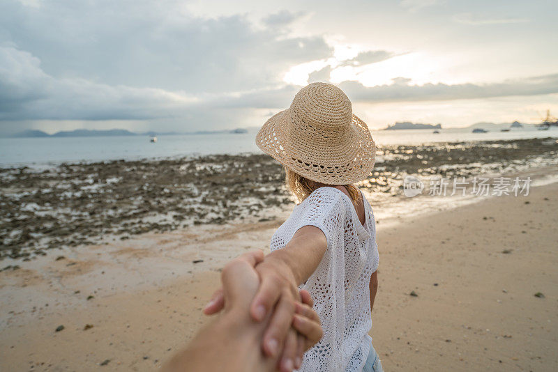 年轻女子带着男子去海滩