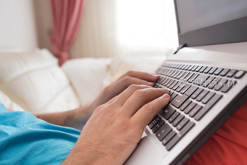 男人的手在家里的笔记本电脑键盘上打字。在网上浏览信息的人。自由博客，它支持概念