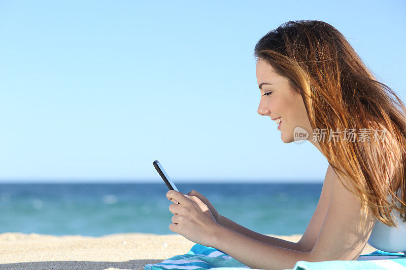 一个女人在海滩上用智能手机发短信