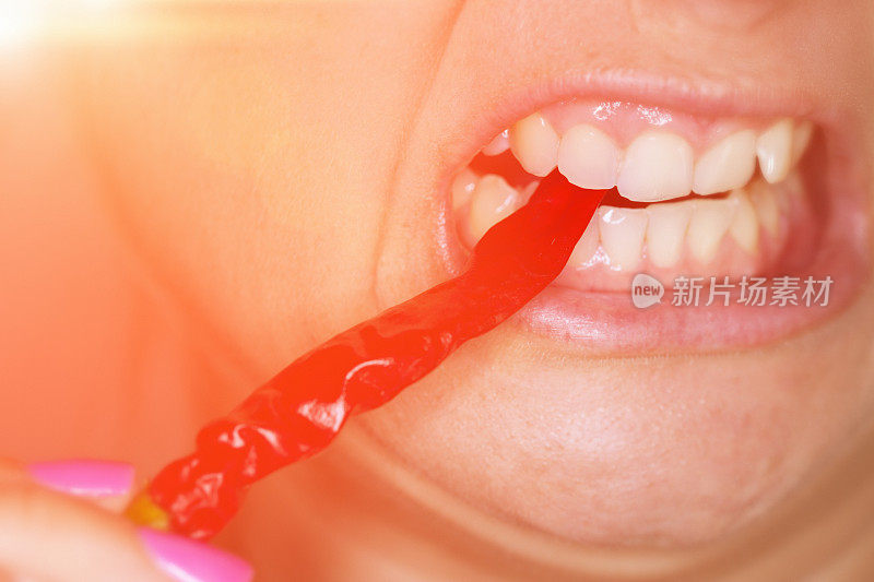 一名女子咬着一个红辣椒，脸上露出痛苦的表情