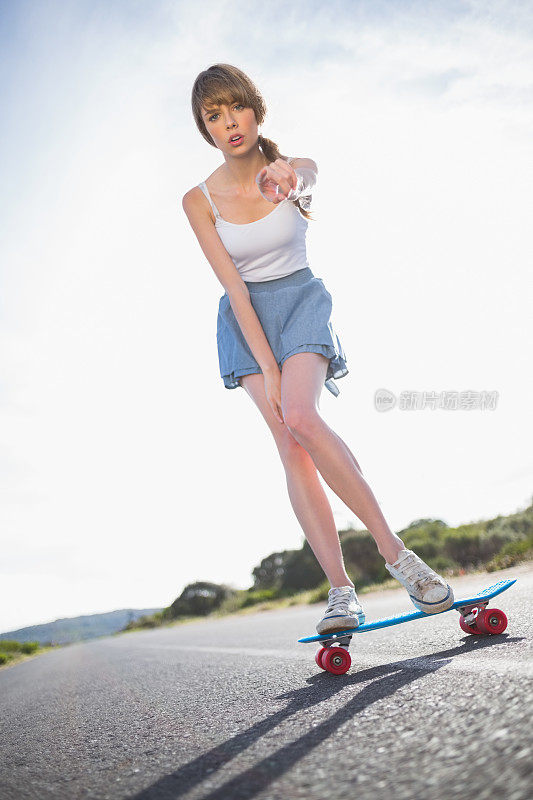 年轻女子在滑板上保持平衡时，指着摄像机