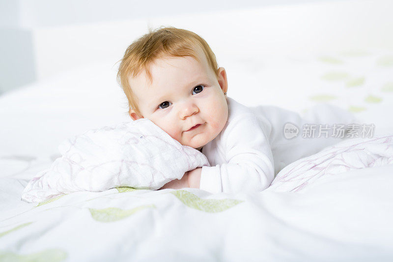在她房间的床上爬行的婴儿的肖像