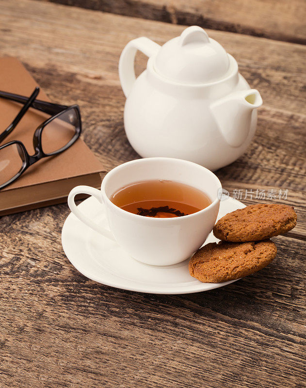 象牙茶杯与甜饼干，眼镜和书在木制调色板上