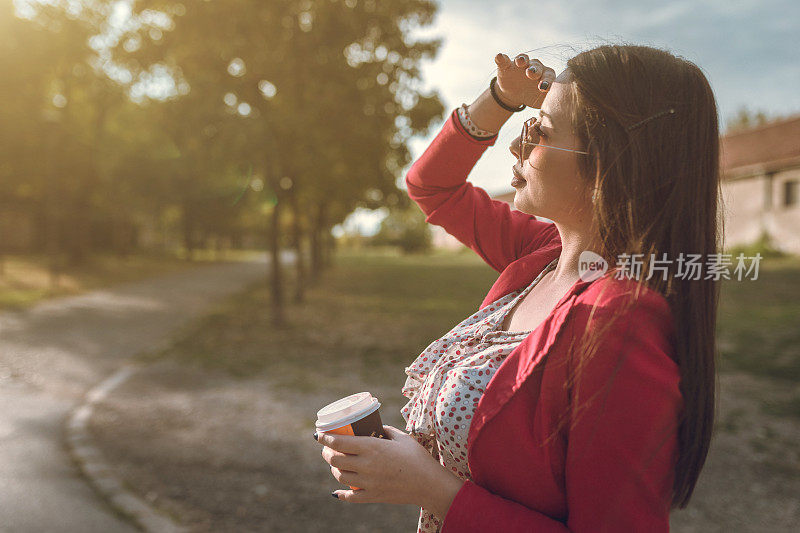 年轻漂亮的女人在公园喝咖啡