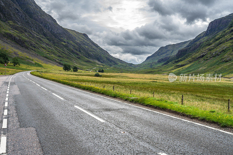 风景优美的格兰科山谷道路与戏剧性的多云的天空，苏格兰高地，英国