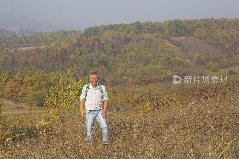 一名成年男子在阳光明媚的印度夏秋日徒步旅行在美丽的大自然中。