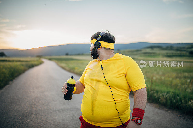 超重男子在慢跑后喝水休息