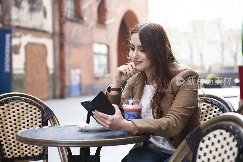 在咖啡馆外拿着智能手机的女人