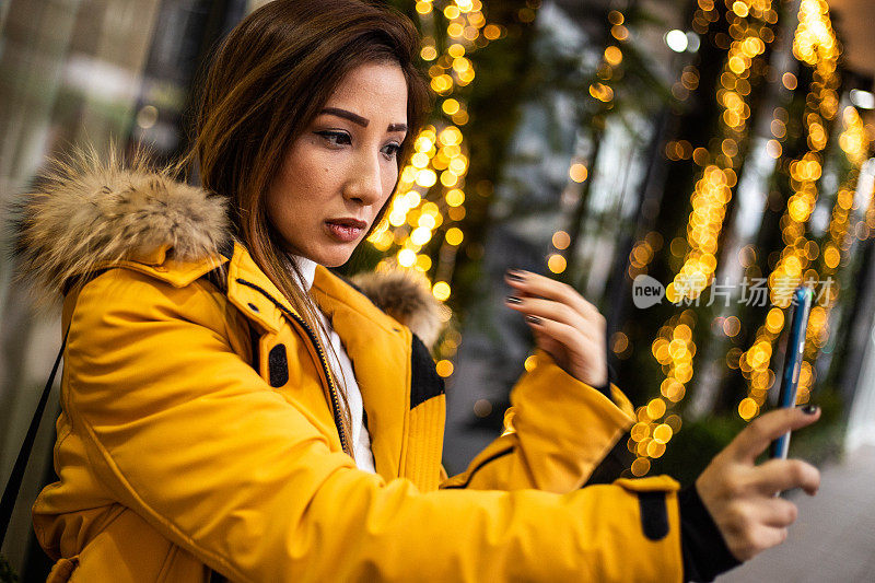 美丽的亚洲女人在圣诞装饰前自拍