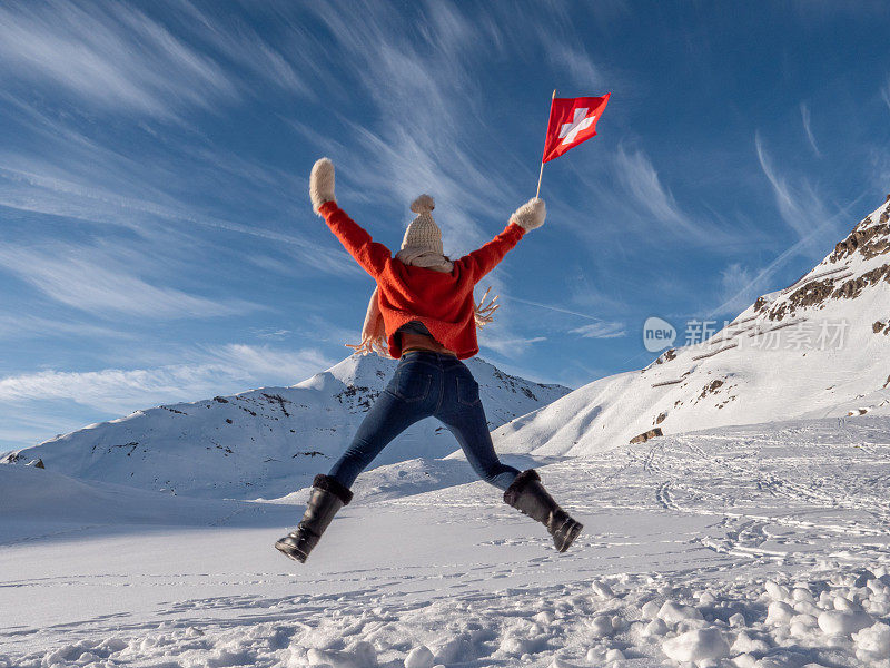 快乐的女人，瑞士国旗在空中跳跃，雪山在冬天