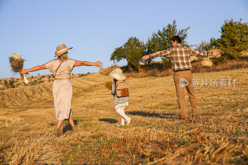 幸福的家庭:母亲，父亲，孩子，女儿自然在秋天日落。幸福的一家人在麦田里散步