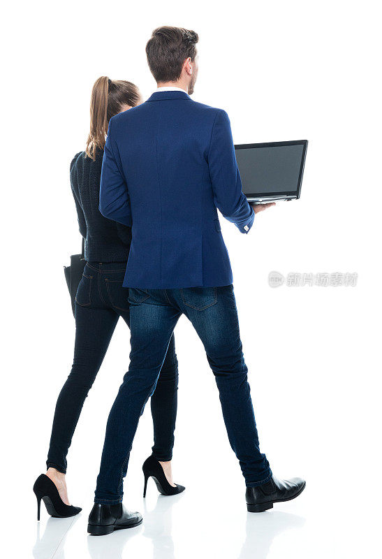 白人年轻男性女商人走在白色的背景，穿着纽扣衬衫，拿着钱包和使用笔记本电脑